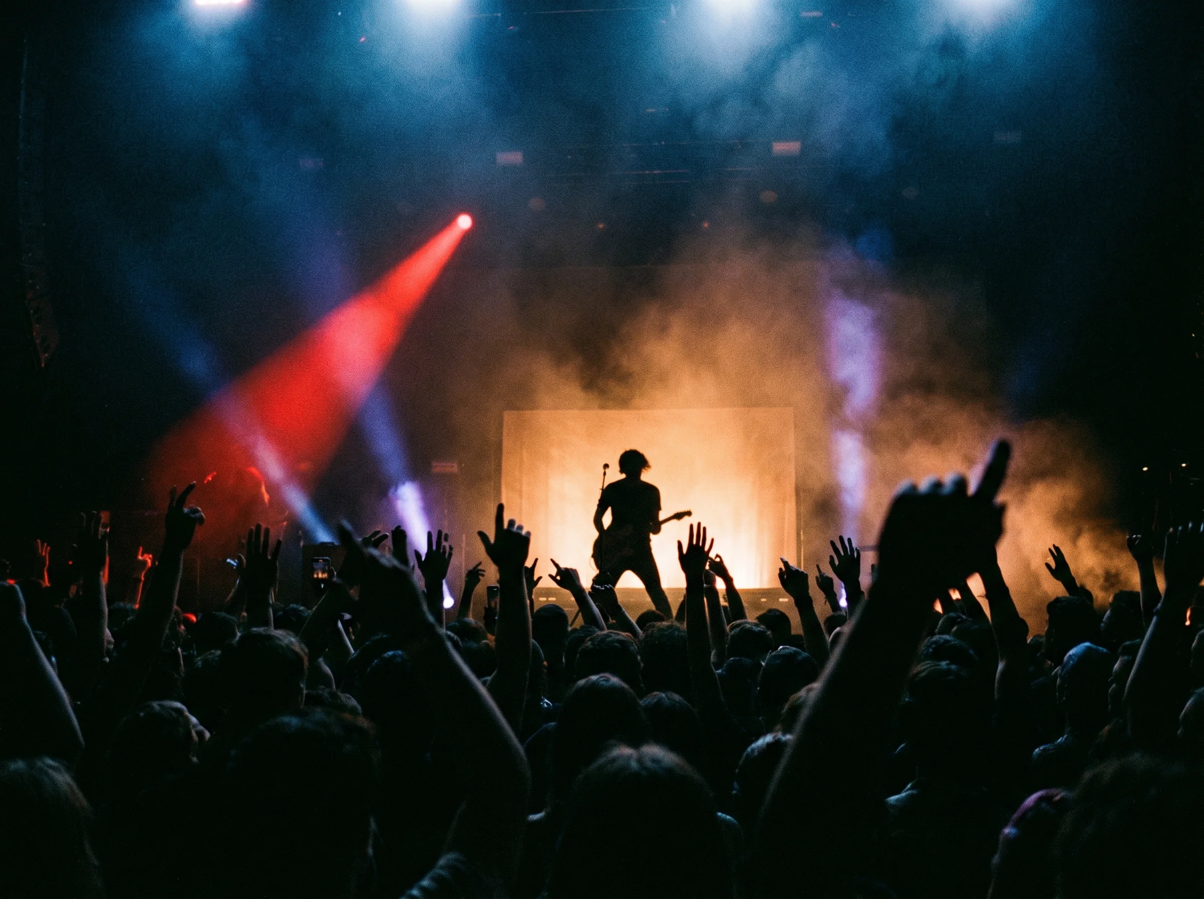 Concert scene with raised hands in red spotlight